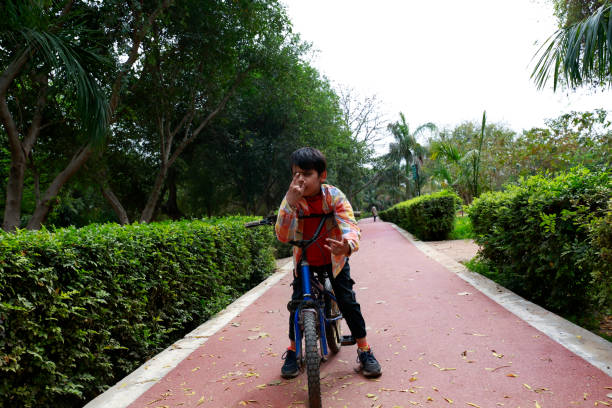 Indian little boy enjoying the cycle ride outdoor in the Park with facial and hand gesture
