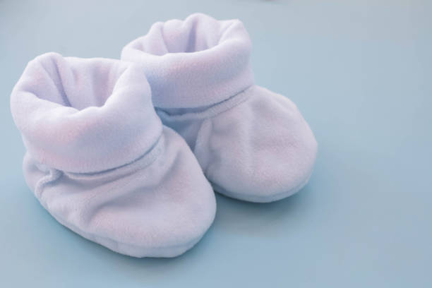 istock Blue booties for a boy on a blue background. Shoes for newborns 1474521184