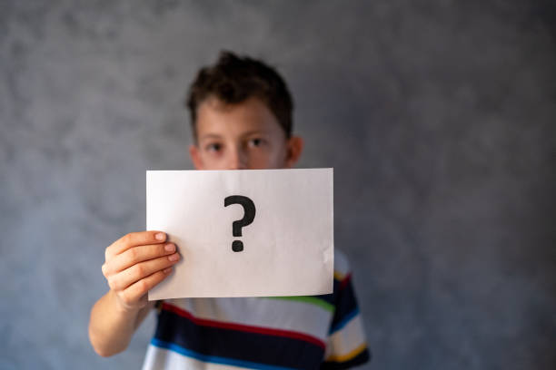 istock Cute boy is thinking and holding a paper with a question mark 1474522568