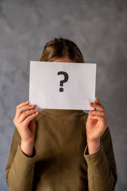 istock Girl covered her face with paper and question mark 1474523306