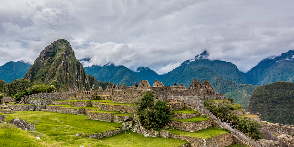 This captivating image showcases the iconic and well-preserved ruins of Machu Picchu, an Incan citadel set high in the Andes Mountains of Peru. The stone structures blend harmoniously with the lush greenery and the dramatic backdrop of steep cliffs, emphasizing the awe-inspiring craftsmanship of the Inca civilization