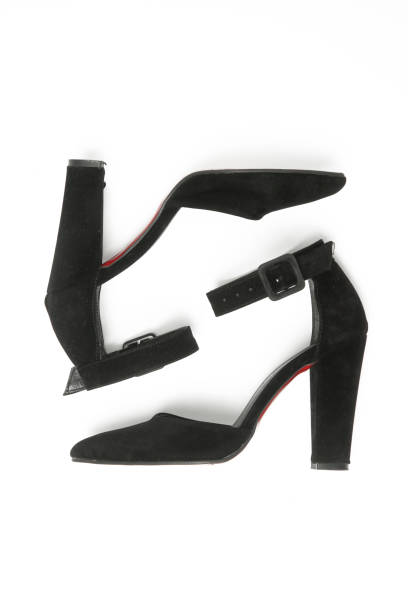 Black women's pointed toe pumps with block high heels and ankle strap, studio shot isolated on white background