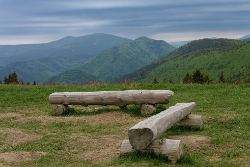 Wooden benches in mountain pass Medziholie in national park Mala Fatra, natural reserve Velky Rozsutec, Slovakia, spring cloudy day.