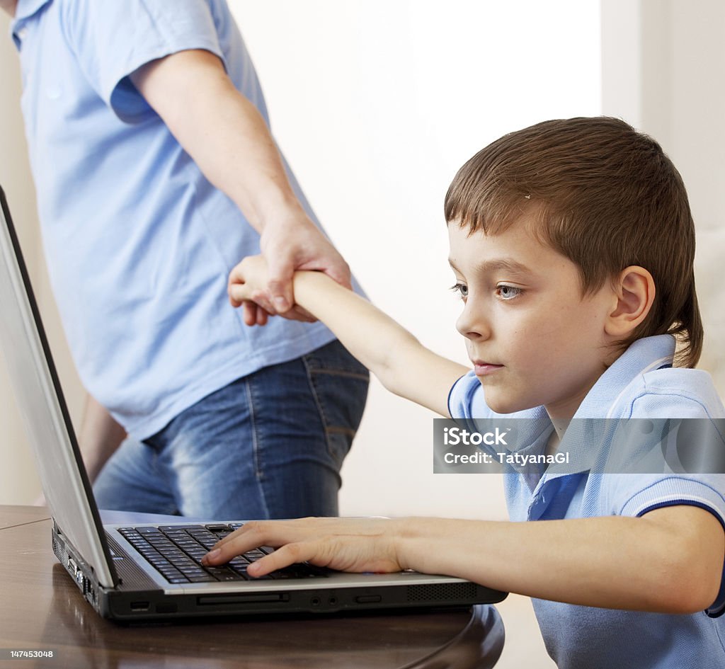 Padre trascinando il figlio dal computer - Foto stock royalty-free di Bambino