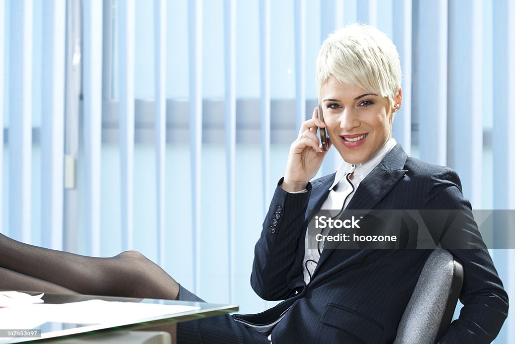 Businesswoman Businesswoman with feet on desk talking on mobile phone. 25-29 Years Stock Photo