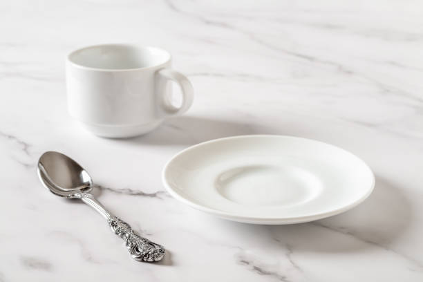 istock Empty white plate, cup and spoon on a marble table. Clean porcelain crockery for food design mockup. Breakfast, eat and drink, tableware concept. High key image. 1474546209