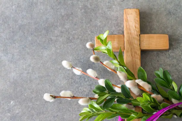 Wooden cross and easter palm tree made of catkins and boxwood, palm sunday concept background