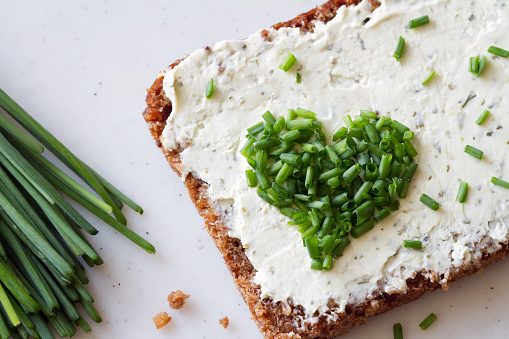 Sandwich with cream cheese and heart-shaped chives, concept background