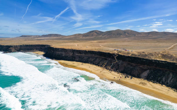 aerial high level panoramic view of the rocky cliffs and beaches with the volcanic mountain backdrop near el cotillo in fuerteventura spain - el cotillo imagens e fotografias de stock