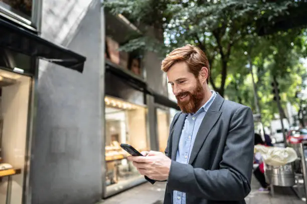Photo of Businessman using smartphone outdoors