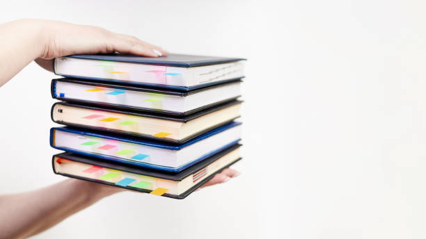 istock An office employee holds in his hands a stack of notebooks with colorful bookmarks on a light background 1474557557