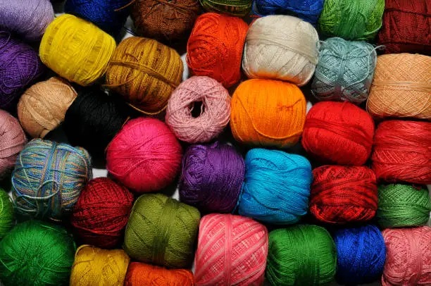 Multi-colored crochet-knitting threads, wound in many balls on a desk