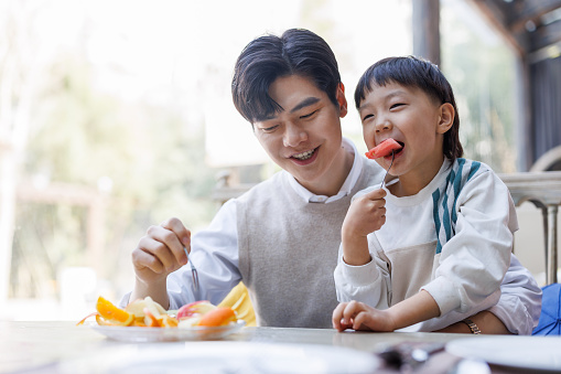 The young father hugged his son and ate watermelon together