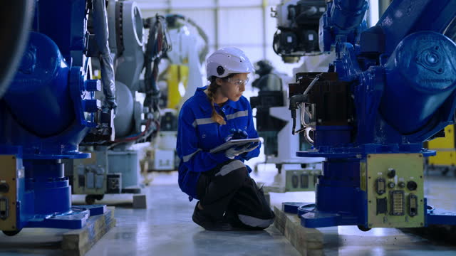 Engineer examining welding robot in plant warehouse.