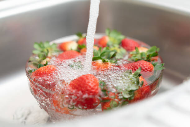 台所の流しでイチゴを洗う - washing fruit preparing food strawberry ストックフォトと画像