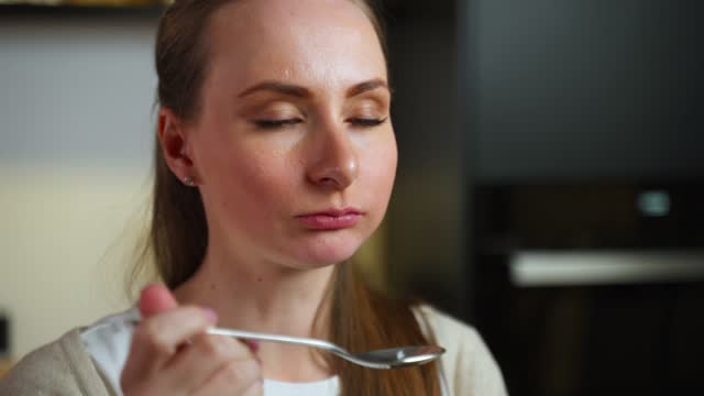 Close-up portrait of an attractive healthy young woman eating indoors, holding a fork with a delicious snack