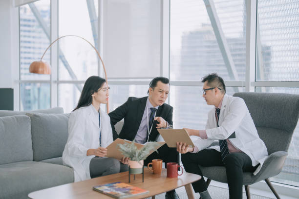istock Asian hospital senior management questioning doctors on the documents agreement in lobby sofa 1474589529