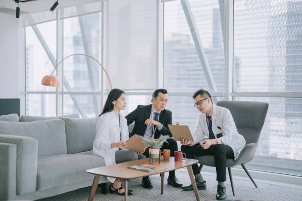 istock Asian hospital senior management questioning doctors on the documents agreement in lobby sofa 1474589532