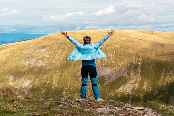 женщина, достигающая места назначения и на вершине горы на фоне облачного голубого неба в осенний день путешествия концепция образа жизни � - english lake district orienteering hiking mountain стоковые фото и изображения