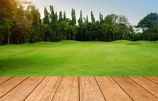 Wooden floor and golf course background. Fresh spring green golf course with wood floor. Beauty natural background, Empty wooden deck table with Green background.