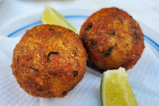Two cod fritters accompanied by two pieces of lemon
