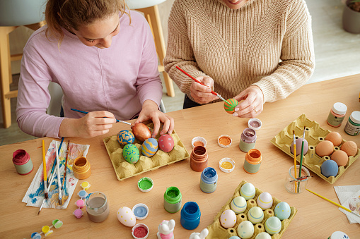 High angle view of a mother and daughter having fun painting Easter eggs at home. High resolution 42Mp indoors digital capture taken with SONY A7rII and Zeiss Batis 40mm F2.0 CF lens