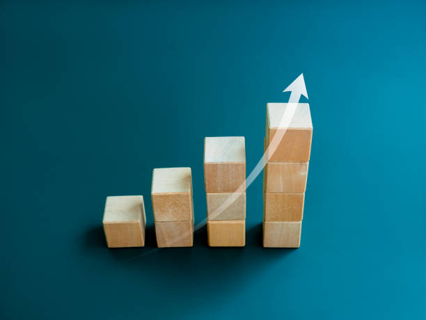 istock White rising up arrow draw on wooden cube blocks bar graph chart steps on blue background, minimal style. Purchase trend increase, income, inflation, business marketing growth concepts. 1474603878