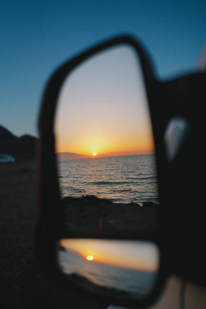 istock Reflection of sun setting over sea in side mirror 1474604688