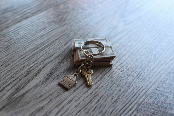 istock Selective focus image of house shaped keychain and stack of money. 1474605917