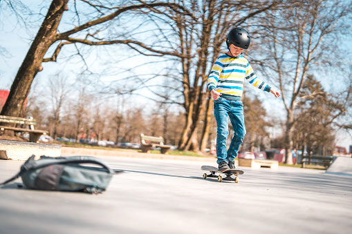 Mixed race skater boy riding a skateboard in a skate park. He is wearing a helmet.