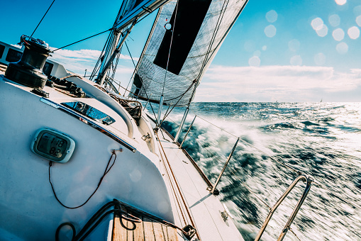 Group of friends diving in the water during a sailboat excursion, young people jumping inside ocean in summer vacation from a sail, having fun, luxury vacation lifestyle