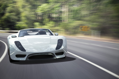 A white sports car travelling fast on a winding forest road. This car is designed and modelled by myself. Very high resolution 3D render composite. All markings are ficticious.