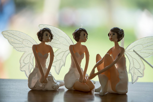 Three angel figure dolls with wings on wooden table with natural background