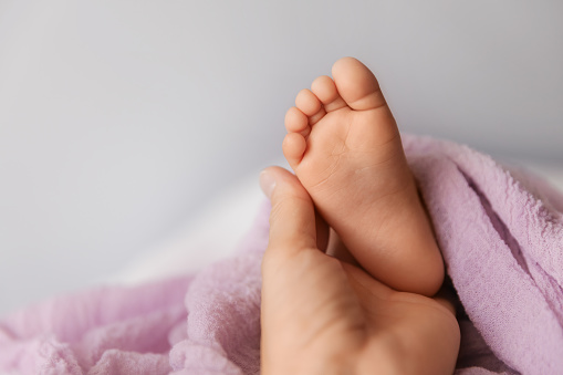 Closeup of tiny foot in mother's hand, candid babyhood and motherhood concept - Image