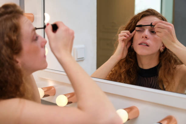 Young ballerina applying mascara in front of the mirror. stock photo