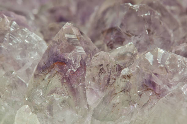 Light pale colored Amethyst quartz crystals in raw mineral form with selective focus. Fine details and textures abstract background.