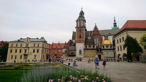 Krakow, Poland - Jun 10 2018: Tourists in the Zamek Krolewski na Wawelu, Wawel Royal Castle, with a garden in the front and the Wawel Cathedral in the centre