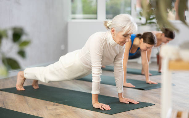 istock Elderly woman holding plank pose during group yoga training 1474630541