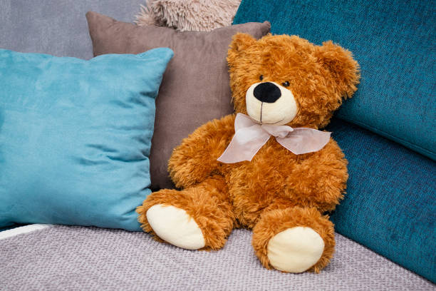 istock Brown, toy teddy bear with colored pillows on a blue sofa 1474631968