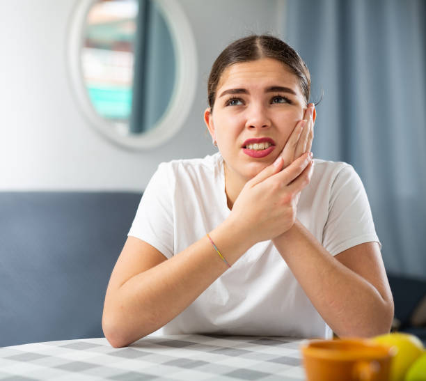 istock Sick woman experiencing severe pain in tooth while sitting at table 1474632495