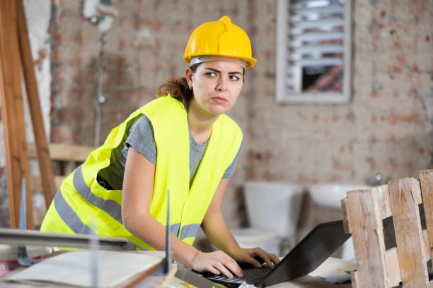 istock Female contractor using laptop to check plan of building under construction 1474633267