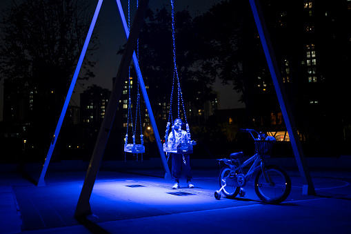 Little girl playing on a glowing swing