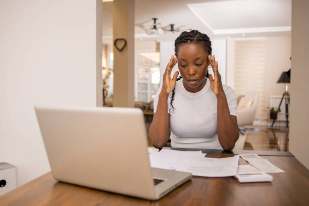 istock Young woman using calculator while going through bills and home finances 1474640299