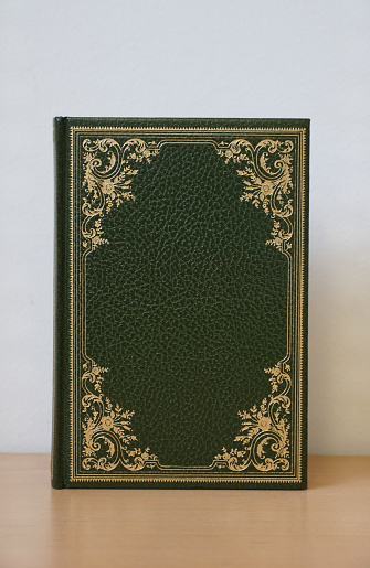 Green leather cover old vintage books with decorative details of golden tendrils