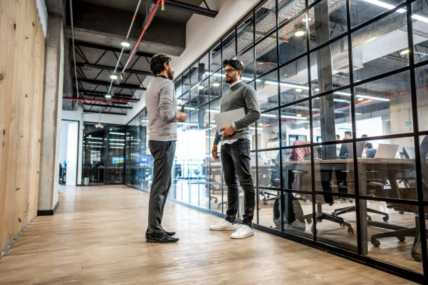istock Coworkers talking in corridor at office 1474644218