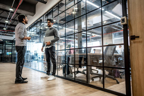 istock Coworkers talking in corridor at office 1474644256
