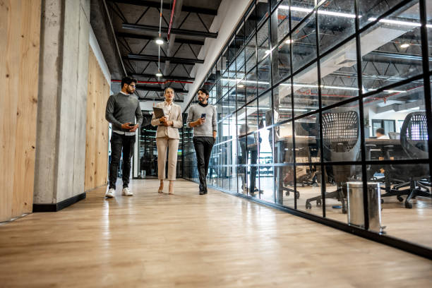 coworkers talking while walking through corridor at office - ceo corporate business indoors lifestyles imagens e fotografias de stock