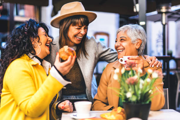 heureux trois femmes âgées prenant le petit-déjeuner en mangeant des croissants et en buvant du café à la cafétéria du bar de la ville, style de vie et concept d’amitié avec des femmes matures s’amusant à l’extérieur assises à table - dining senior adult friendship mature adult photos et images de collection