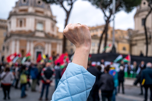Female fist raised in the air while protesting in the street in Rome, Italy