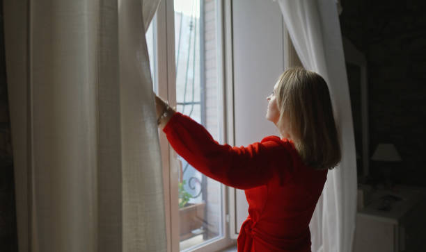 istock Woman opening curtains in her apartment. 1474654739